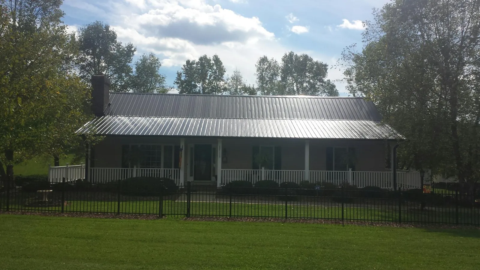 Gray metal roof on a brick ranch with a full width front porch — Gutter Guard Installation work by our crew in Shepherdstown