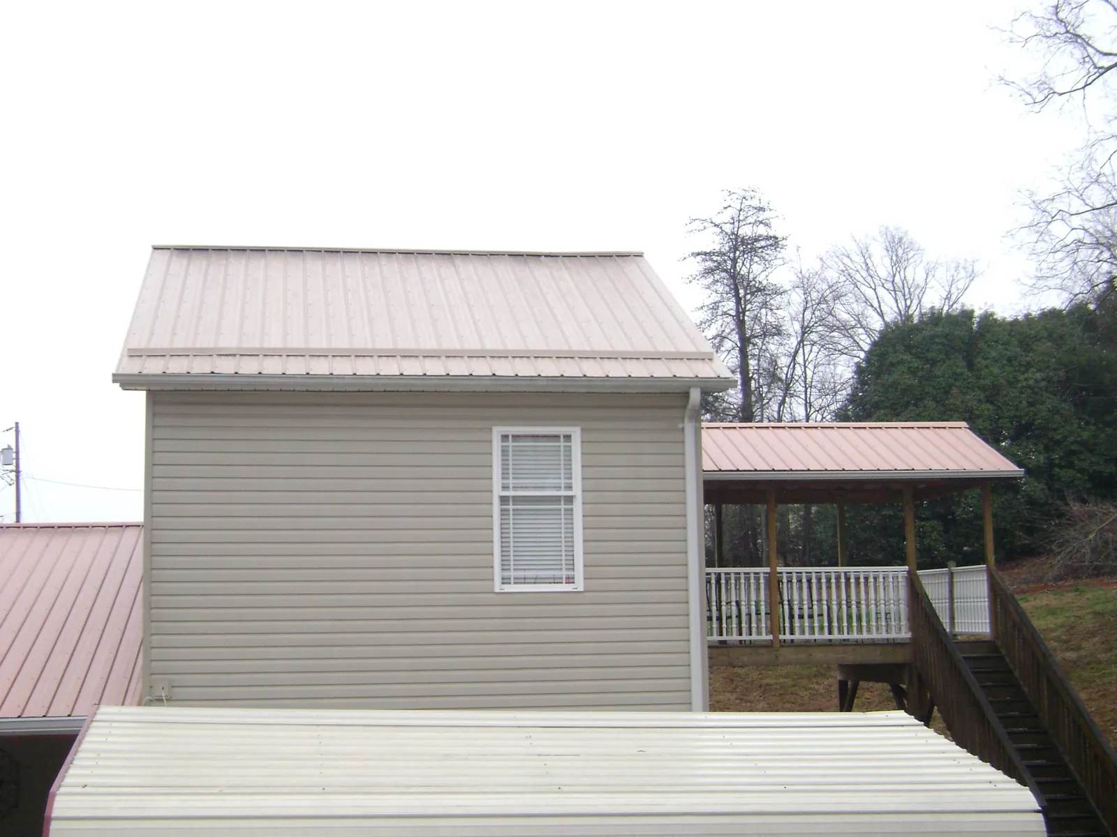 Tan metal roofs on a two story addition and attached porch, from a Roof Replacement job in Shepherdstown