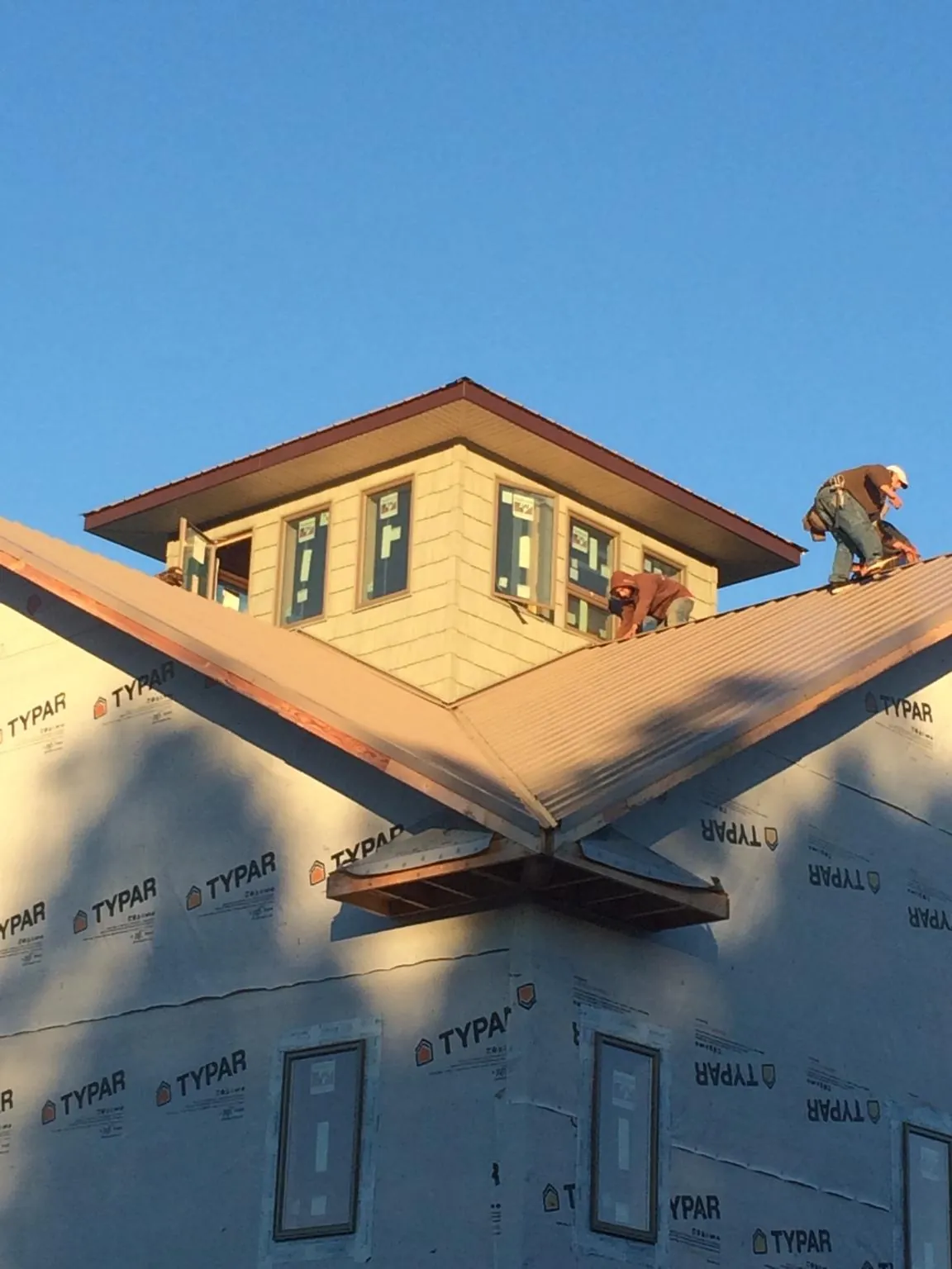Roofers working around a rooftop cupola on a new metal roof at sunset — Roof Waterproofing in Shepherdstown by Roofing Brothers